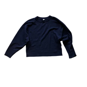 Mörkblå stickad tröja - Nelly - En enkel och stilren mörkblå stickad tröja med loose passform och rund hals. Tröjan har långa ärmar och ribbade muddar vid hals, ärmslut och nederkant. Perfekt för dig som gillar en chill och avslappnad look.