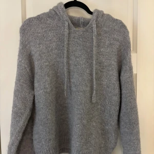 Grå stickad hoodie från Gina Tricot - Mysig grå stickad hoodie från Gina Tricot i storlek XS. Tröjan har huva med snörning och är långärmad. Perfekt för kyliga dagar och enkel att matcha med jeans. Använd ca 2 gånger!