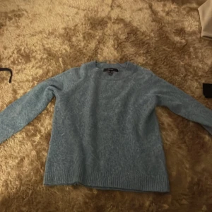 Ljusblå stickad tröja vero moda  - Mysig ljusblå stickad tröja från vero moda  med rund halsringning och långa ärmar. Tröjan har ribbade muddar vid ärmslut och nederkant, perfekt för lager-på-lager och chill dagar.