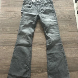 Grå bootcut jeans Low Boot L - Snygga grå jeans i bootcut-modell från Low Boot, storlek L med full längd. Byxorna har låg midja och är både sköna och bekväma. Nya med prislapp, aldrig använda. 