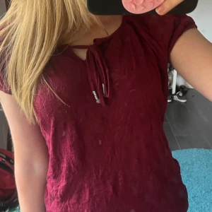 Vinröd topp med knyt i halsen - Säljer en vinröd topp med korta ärmar och snygg knytning vid halsen. 💗