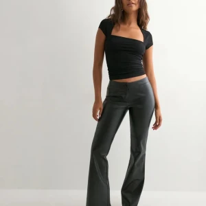 Svarta bootcut byxor i skinnimitation - Snygga lågmidjade skinnbyxor från Nelly. Använda ett fåtal gånger och är som nya! Orginalpris 499 