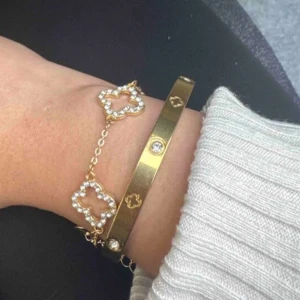 Guld armband  - Snyggt armband i guld med flera fyrklöverformade dekorationer,  dekorerade med glittrande stenar. 