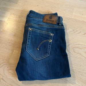 Mörkblå skinny jeans från Dondup - Snygga mörkblå jeans från Dondup med klassisk femficksdesign och coola kontrastsömmar. Modellen är skinny/slim med mindre passform och har en läderpatch med logga bak i midjan. Jeansen är tillverkade i mjukt denimtyg som sitter skönt hela dagen. Passar runt 165cm lång
