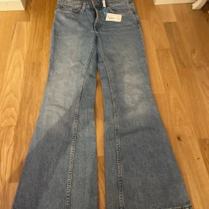 Blå bootcut jeans från Weekday - Snygga ljusblå jeans från Weekday i modellen Wave. Jeansen har bootcut passform med utsvängda ben och klassisk femficksdesign. Tillverkade i bomull med tydliga sömmar och normalhög midja. Perfekta för en trendig och avslappnad look.