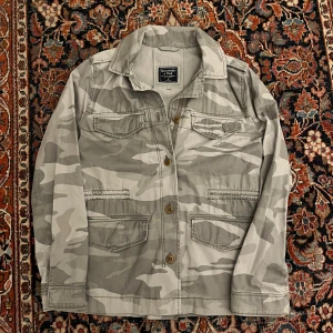 Abercrombie and fitch camo jacka - Riktigt fet Abercrombie and fitch jacka, denna är perfekt för hösten och har en riktigt skön ljus camo färg på sig! Den är M men sitter mindre som en S Mått: Bredd: 47cm Längd: 66cn
