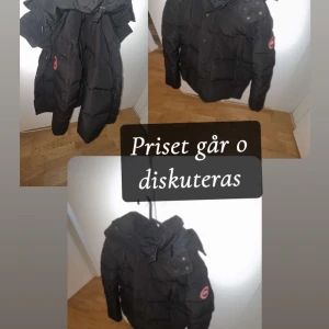 Svart pufferjacka från Canada Goose - Säljer en svart pufferjacka från Canada Goose med huva och klassisk logga på ärmen. Jackan har långa ärmar, flera fickor och en snygg, quiltad design som håller dig varm under kalla dagar. Perfekt för dig som vill ha en stilren och funktionell vinterjacka.