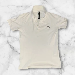 Vit Replay t-shirt med krage - Snygg vit t-shirt från Replay med klassisk krage och knappslå framtill. T-shirten har korta ärmar och en liten logotyp på bröstet. Perfekt för dig som gillar stilrena och enkla plagg med en touch av märke.