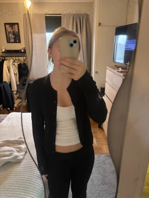 Svart kofta från 157, storlek M - En svart, klassisk kofta från 157 i storlek M. Koftan har rund halsringning, knappar hela vägen framtill och långa ärmar. Enkel och stilren design som funkar till det mesta.Endast använd 2gånger