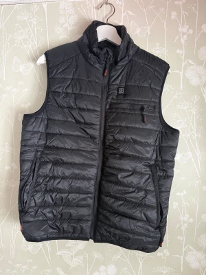 Genzo svart elektronisk dunväst - Oanvänd värmeväst som drivs av powerbank (medföljer en pawerbank och laddare), har bra passform. Perfekt för jakt, fiske, vandring eller bara för att slippa frysa. Pris går att diskutera 