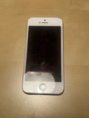 iPhone 5 blockerad iCloud  - Apple iPhone 5 ICLOUD BLOCKERAD vit/silver färg. Skärmen har några repor, baksidan och kanterna visar lätt slitage. Klassisk design med hemknapp och 8MP kamera. Perfekt som reservtelefon eller för samlare. Säljs i normal skick.