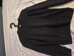 Svart stickad tröja från Defacto - Svart stickad tröja från Defacto med rund hals och långa ärmar. Tröjan har en enkel och clean design med ribbade muddar vid ärmslut och nederkant. Perfekt för dig som gillar basic och stilrent.