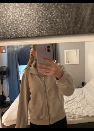 Hoodie - Säljer en beige hoodie med huva och dragkedja framtill. Tröjan har långa ärmar, ribbade muddar och fickor på sidorna. Perfekt för chill dagar och enkel att matcha med jeans eller leggings. Materialet känns mjukt och skönt mot huden.