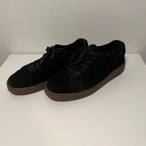 Vagabond sneaker svart brun - Svarta sneakers från Vagabond med ovandel i mjuk mocka och bruna platta gummisulor. Klassisk rund tå och snörning framtill. Perfekt för dig som gillar stilrena och enkla skor med en modern touch. Prisvärda & Felfria ✅| Passar 45 | Vid fundering skicka PM ⚠️| Pris kanske kan diskuteras 🤝