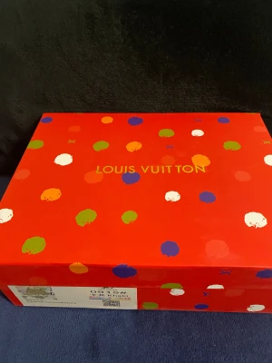 Beige axelväska från Louis Vuitton - Snygg beige axelväska från Louis Vuitton med guldiga metalldetaljer och stort LV-emblem framtill. Väskan är tillverkad i strukturerat skinn och har en stilren, boxig form med axelrem. Perfekt för dig som vill ha en lyxig och trendig accessoar. Använd kanske 4-5 gånger