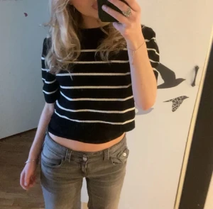 Svartvit randig croppad topp - Säljer en svart croppad topp med vita horisontella ränder. Toppen har korta ärmar och rund halsringning. Perfekt för dig som gillar en enkel men snygg stil. Passar till både jeans och kjol.