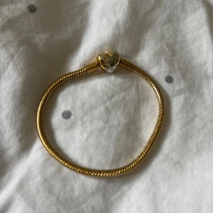 Pandora armband guld - Super fint Pandora armband, storlek 17 (17cm). Har tappat lite färg på låset, men annars väldigt bra skick. Köpte det av en annan tjej som säger att det är äkta, men kan då inte garantera. (Har bild på kvittot som jag fick av henne) skriv privat för frågor och bilder!💗💗/säljer då det inte kommer till användning!