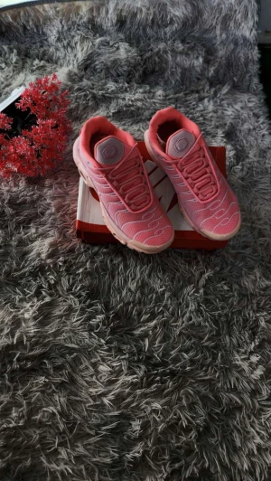 Nike Air Max rosa sneakers - Nike Air Max sneakers i en fräsch rosa färg med ljusa detaljer och vita vågiga mönster på ovansidan. Skorna har synliga luftkuddar i sulan, snörning och en rund tå. Ovandelen är i mesh och syntet för bra ventilation och komfort. Perfekt för dig som gillar sportig och trendig stil.