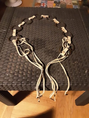 Beige och brunt bälte med ringar - Unikt bälte med stora bruna ringar länkade med beige mockaband och långa fransar. Bältet har en bohemisk vibe och passar perfekt för att ge outfiten en cool twist. Justerbar längd tack vare de långa mockasnörena.248 lång