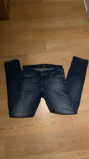 Jack & Jones slim Glenn - Snygga blå jeans från Jack & Jones med super stretch för extra komfort. Modellen har klassisk femficksdesign, smal passform och subtila slitningar framtill. Perfekt för dig som gillar stilrena och bekväma jeans med lite extra stretch.