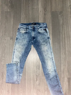 Replay ljusblå skinny jeans - Säljer ett par Replay jeans i ljusblå tvätt med snyggt slitna detaljer och klassisk femficksdesign. Modellen är skinny med smal passform och normal midja. Jeansen har dragkedja och knapp framtill samt Replay-logga på fickan. Midja storlek 32, Längs storlek 36