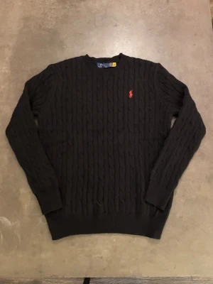 Polo Ralph Lauren kabelstickad tröja - Storlek L, skulle säga att den passar mer som M. Svart kabelstickad tröja från Polo Ralph Lauren. I princip ny, använd ett fåtal gånger och då sparsamt! Vid fler frågor skicka ett pm! 