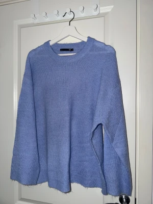 Ljusblå stickad tröja från 157 - Mysig ljusblå stickad tröja från 157 i storlek M. Tröjan har rund hals, ribbade muddar och en loose passform som ger en chill vibe. Perfekt för att hålla sig varm under kyliga dagar. Enkel och stilren design utan mönster.