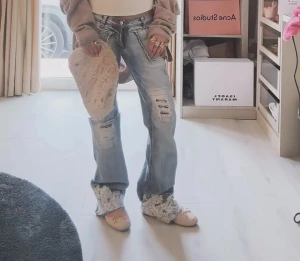 Blå slitna jeans med spetsdetaljer - Innerbenslängd: 77 cm Midjemått: 35 cm