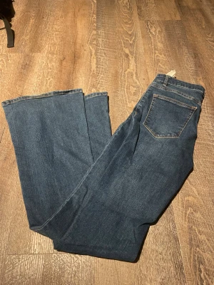 Blå wide jeans från Pull&Bear - Säljer ett par blå jeans från Pull&Bear i storlek 36. Modellen har breda ben och klassisk femficksdesign med kontrastsömmar. Jeansen är tillverkade i jeansmaterial och har en snygg, mörkblå tvätt som passar till många olika stilar.