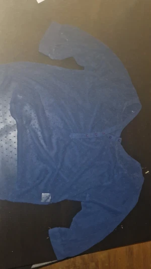 Blå henley från Rut m.fl. strl 38 - Blå henley-skjorta från Rut m.fl. i storlek 38. Skjortan har lång ärm, lila knappar framtill och ett diskret prickigt mönster i tyget. Materialet känns lätt och luftigt, perfekt för dig som gillar en chill och enkel stil.(vet inte hur många gånger den används men känns ny)jag köpte den på secondhand men har bara använt den 1 gång själv efter det