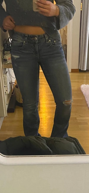 Blå low jeans från Gina Tricot med slitningar - Helt nya Snygga blå jeans från Gina Tricot. De har låg midja, raka ben och slitningar vid knäet och fickan. Baksidan har detaljerade fickor med kontrastsömmar och silverknappar. Skriv för mer bilder eller frågor! Briser kan diskuteras💞