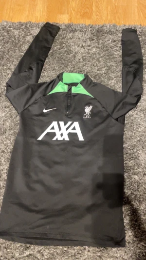 LFC träningströja - Tja, säljer en långärmad träningströja från Liverpool FC.   Slim fit modell (S/M) som passar perfekt vid tex fotbollsträning.   Tröjan är tillverkad i Dri-FIT polyester som andas väldigt bra.  Mycket fint skick!  Vid frågor är det bara att höra av sig! Köpt på unisport.