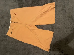 Beiga bermudashorts från Pret a Porter - Säljer ett par beiga bermudashorts från Pret a Porter i klassisk modell. De har normal passform, raka ben och stängs med knapp och dragkedja. Perfekta för varma dagar och enkla att matcha med det mesta.