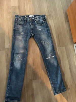 Replay Anbass slim fit jeans blå - Snygga blå Replay Anbass jeans i slim fit med slitna detaljer och lagom tvättad look. Storlek 31 Annbass använda men fortfarande i väldigt bra skick. Vid fråger eller funderingar är det bara att höra av sig. 