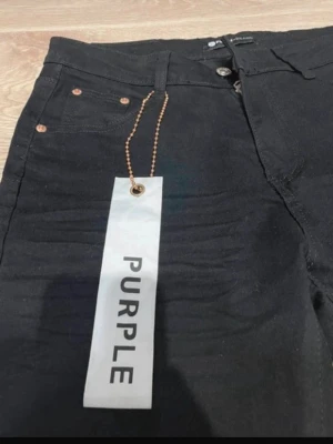 Svarta jeans från Purple Brand - Säljer ett par svarta jeans från Purple Brand med klassisk femficksdesign och snygga kopparfärgade nitar. Jeansen har en rak passform och är tillverkade i ett slitstarkt bomullsmaterial. Perfekta för dig som vill ha en clean och stilren look.