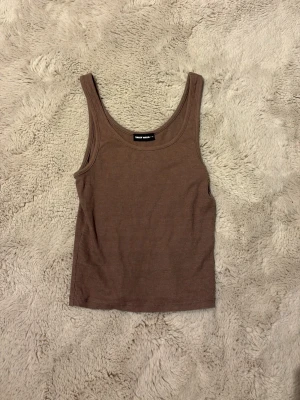 Brun ribbad linnetopp från Weekday - Säljer en brun ribbad linnetopp från Weekday. Toppen är ärmlös med rundad halsringning och har en slim passform. Perfekt att styla till jeans eller kjol för en enkel och snygg look. Vet dock inte vilket märke för jag köpte den i Croatien