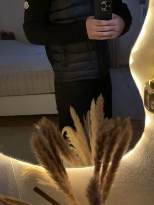 Svart cardigan från Moncler - Svart cardigan från Moncler med quiltad front och stickade ärmar. Jackan har dragkedja hela vägen och en snygg ståkrage. Moncler-logga på vänster ärm. Perfekt för dig som vill ha en clean och modern look. Pris går att diskutera! 