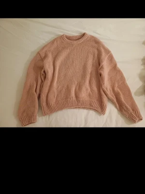  pastellrosa stickad tröja - Mysig stickad tröja i en mjuk, pastellrosa färg. Tröjan har rund halsringning, långa ärmar och ribbstickade muddar vid ärmslut och nederkant. Perfekt för lager på lager och chill dagar.