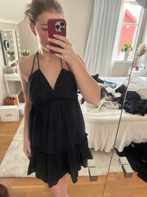 Svart volangklänning med tunna band - Svart halterneck klänning från hm som går att knyta på lite olika sätt. Använd fåtal gånger😊