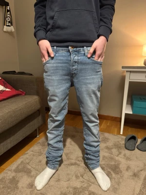 Ljusblå jeans från Jack&jones  - Säljer ett par ljusblå jeans från jj Jeans med klassisk femficksdesign och raka ben. Jeansen har normal passform och är tillverkade i mjuk bomullsdenim. Perfekta för en avslappnad och stilren look.