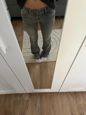 Grå bootcut jeans med kontrastsömmar - Snygga grå jeans från Gina Tricot med bootcut passform och tydliga kontrastsömmar på bakfickorna. Lågmidjade och i klassisk jeansmodell, perfekta för en avslappnad men trendig look. Tillverkade i mjukt bomullsmaterial för skön känsla. Byxorna är i storlek 152.