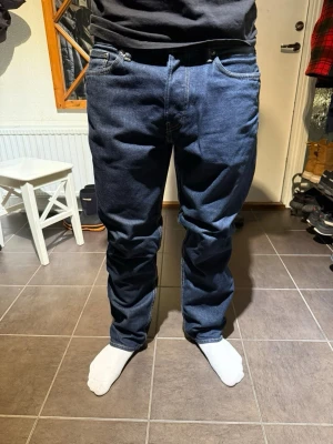 H&M - Säljer ett par klassiska mörkblå jeans från HM med rak passform och fem fickor. Jeansen har normal midja och är tillverkade i slitstark bomullsdenim. Perfekta för dig som gillar en tidlös och enkel stil. W33 L32