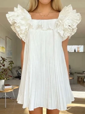 Vit plisserad klänning med volang - Supersnygg vit klänning från Zara med plisserad kjol och stora volangdetaljer vid axlar och halsringning. 💓 så fin till studenten!! kontakta vid frågor annars är det bara och klicka på köp💓