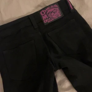 Svarta bootcut jeans från Cheap Monday - Säljer ett par svarta jeans från Cheap Monday med bootcut passform. Klassisk femficksmodell med lila logga bak i midjan. Snygg låg midja och raka ben som släpper ut vid ankeln. Perfekta för dig som gillar en stilren look med edge. Storlek 26/32 men skulle säga att den är lite små sår mer som en 25 passar mig som är 166 perfekt i längd 