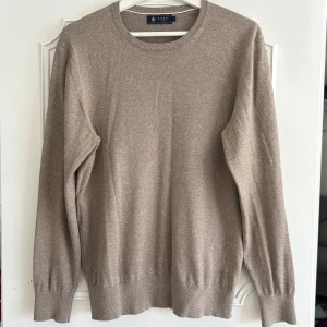 Beige  tröja från Riley - Säljer en stilren beige stickad tröja från Riley i storlek M. Tröjan har rund halsringning, ribbade muddar och är långärmad. Perfekt för lager-på-lager och funkar till jeans eller chinos. Modellen är 180 cm och 67 kg
