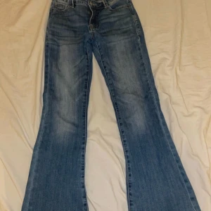 Blå bootcut jeans från Madlady - Snygga blå bootcut jeans från Madlady i storlek EU34/Short. Jeansen har klassisk femficksdesign, normalblå tvätt och utsvängda ben och låg midja.