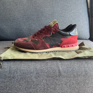 Valentino Rockrunner sneakers i röd och svart - Säljer ett par Valentino Rockrunner sneakers i rött och svart mix. Dom har lite tecken på användning men igen big deal. Box och dustbag följer såklart med! Priset är inte hugget i sten. Tveka inte på att höra av dig om nån fundering!👍