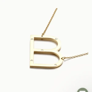 SÖKER !!!’Guldigt halsband med bokstaven B - SÖKER!!! Stilrent halsband med en stor bokstav B som hängsmycke i guldtonad metall. Bokstaven är dekorerad med små glittrande stenar som ger extra bling. Perfekt för dig som vill ha ett personligt smycke med initial.