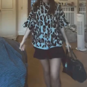 Svart kortkjol med volang - Svart kortkjol med volangkant som ger en cool och lekfull vibe. Kjolen har en tight passform upptill och faller snyggt med volang nedtill. Perfekt att matcha med en oversized t-shirt eller hoodie för en trendig look.