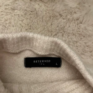 Ljusbeige polotröja från Reserved - Säljer en ljusbeige polotröja från Reserved i storlek L. Tröjan är ribbstickad med lång ärm och hög krage, perfekt för lager-på-lager. Enkel och stilren design som passar till det mesta.